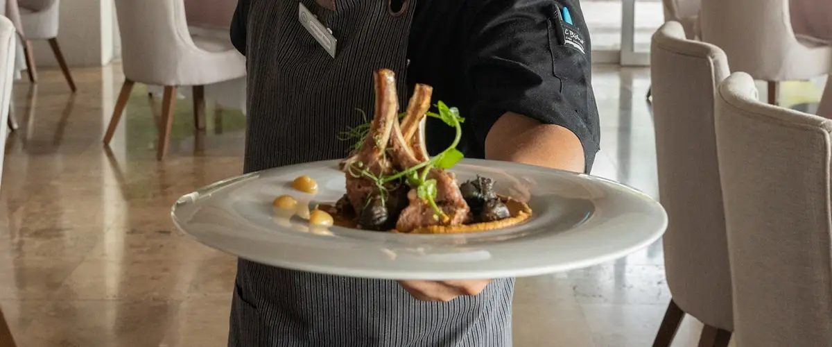 Un chef mostrando un platillo de chuletas de cordero en el Restaurante Gaviotas.