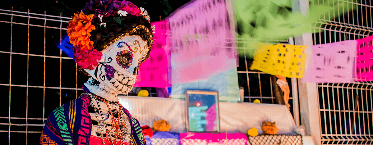 A Day of the Dead altar featuring a beautifully decorated Catrina figure surrounded by papel picado and other traditional offerings.