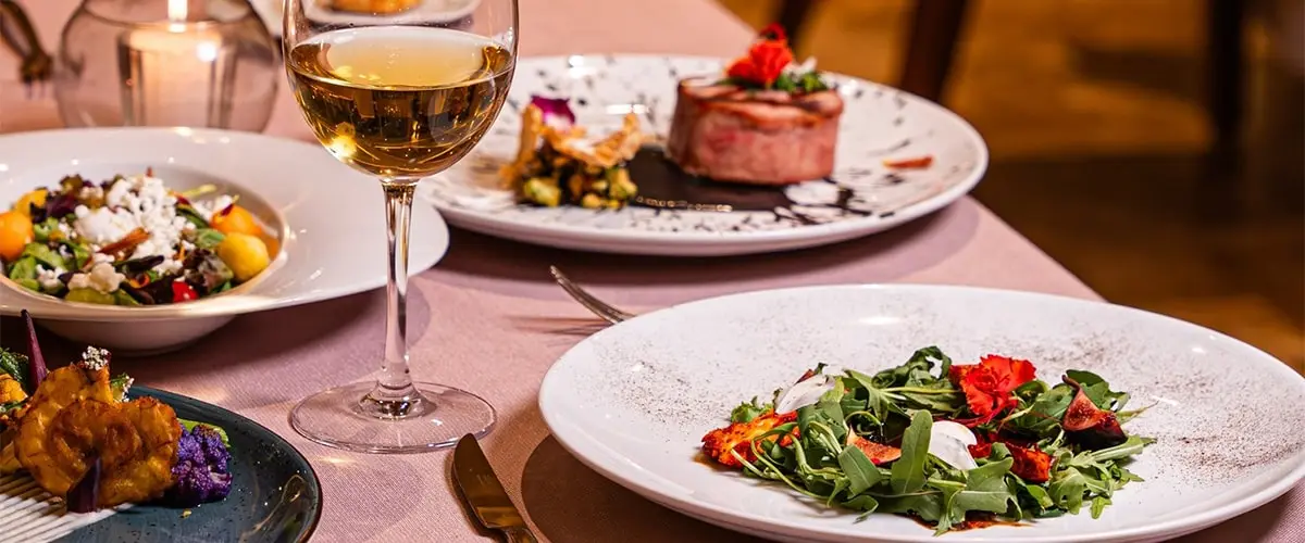 Una mesa con una variedad de platos, incluyendo un bistec, una ensalada y una copa de vino.